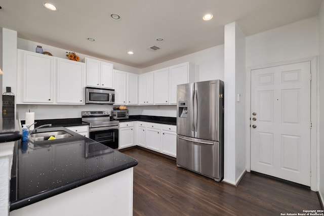 kitchen featuring sink, white cabinetry, stainless steel appliances, dark stone counters, and dark hardwood / wood-style floors