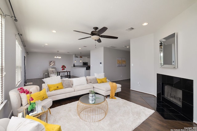 living room with ceiling fan, dark hardwood / wood-style flooring, and a tile fireplace