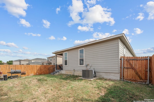 rear view of house with a yard and central AC unit