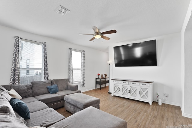 living room with a textured ceiling, hardwood / wood-style flooring, ceiling fan, and a wealth of natural light