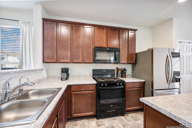 kitchen with black appliances, a sink, and light countertops