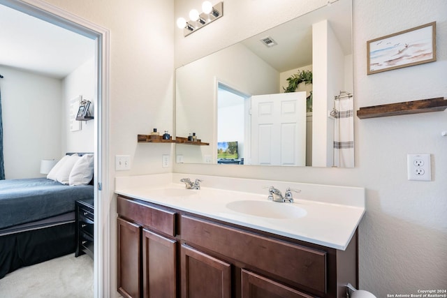 ensuite bathroom featuring connected bathroom, a sink, visible vents, and double vanity