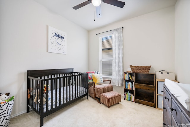 carpeted bedroom featuring a crib and ceiling fan