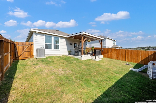 back of property featuring cooling unit, a patio area, a lawn, and ceiling fan