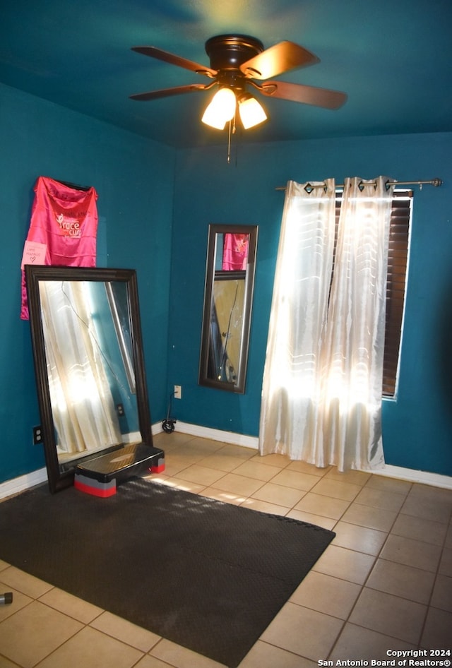 exercise area with tile patterned floors and ceiling fan