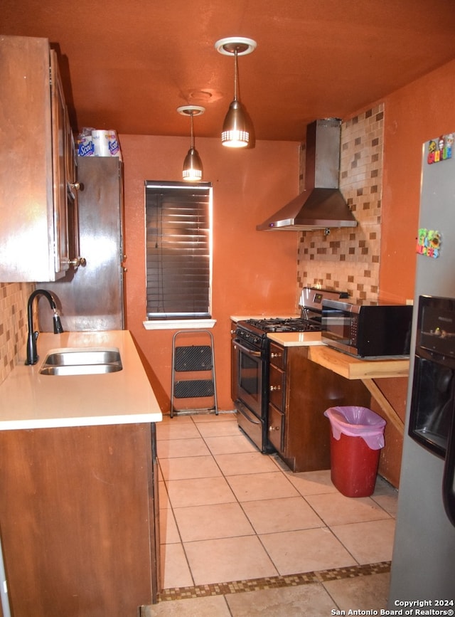 kitchen featuring appliances with stainless steel finishes, sink, wall chimney exhaust hood, pendant lighting, and decorative backsplash