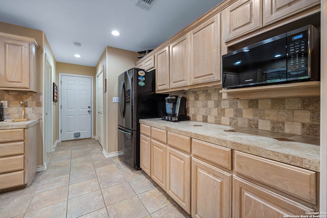 kitchen featuring light brown cabinets, tasteful backsplash, black appliances, and light tile patterned floors