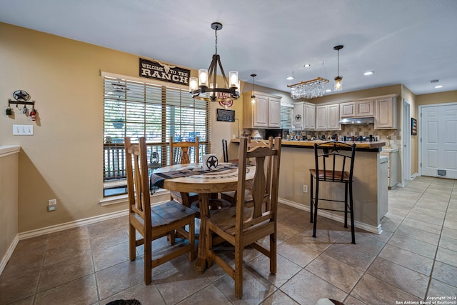 dining space with dark tile patterned flooring and a chandelier