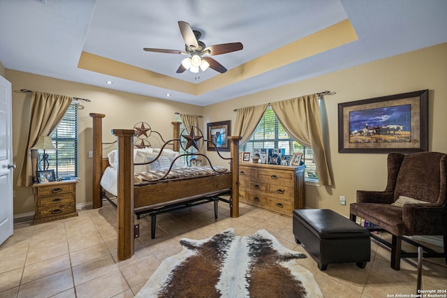 bedroom featuring ceiling fan, a tray ceiling, and light tile patterned floors