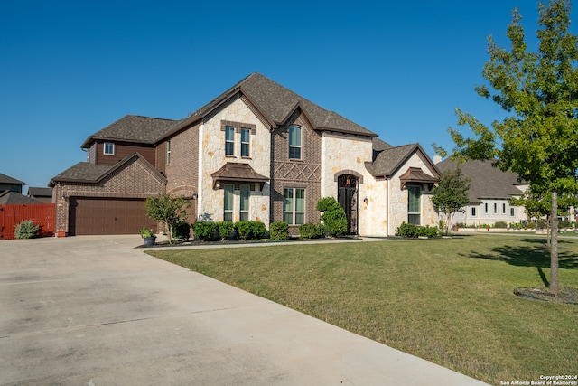 french provincial home featuring a front yard and a garage