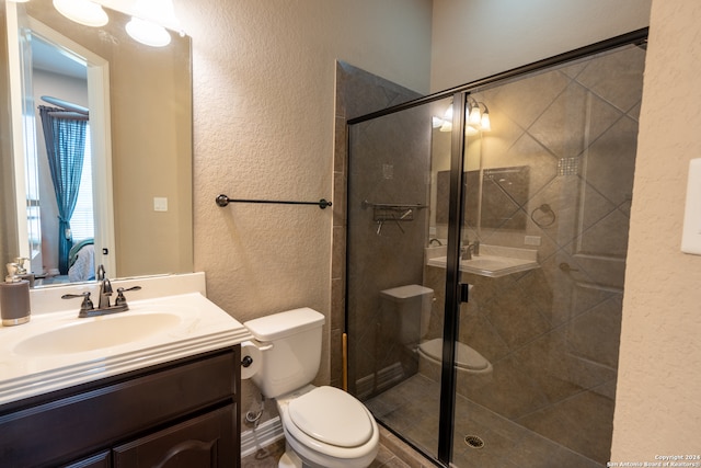 bathroom featuring a shower with door, toilet, and vanity