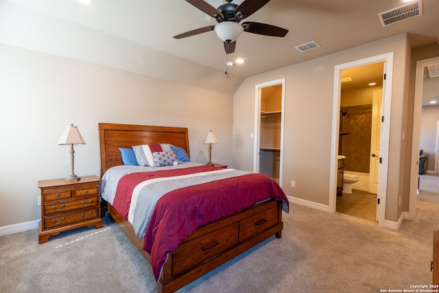 bedroom featuring ceiling fan, a spacious closet, connected bathroom, a closet, and light colored carpet