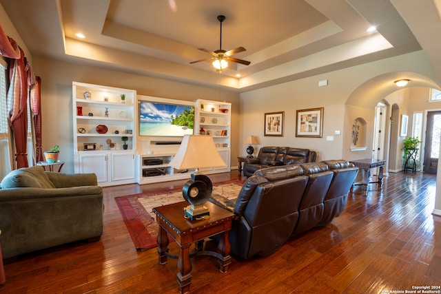 living room with dark hardwood / wood-style floors, ceiling fan, and a raised ceiling