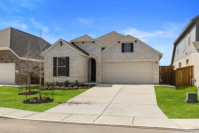 french provincial home featuring fence, concrete driveway, a front yard, and brick siding