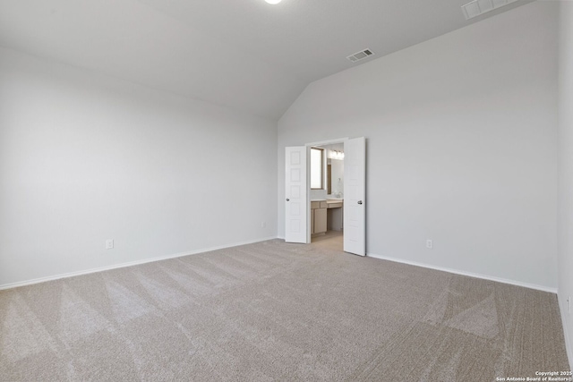 spare room with lofted ceiling, visible vents, baseboards, and carpet floors