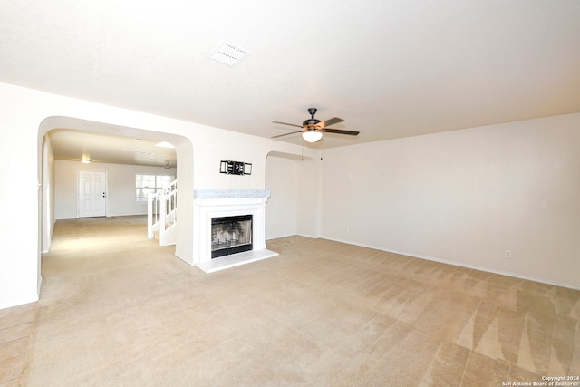 unfurnished living room featuring light carpet and ceiling fan