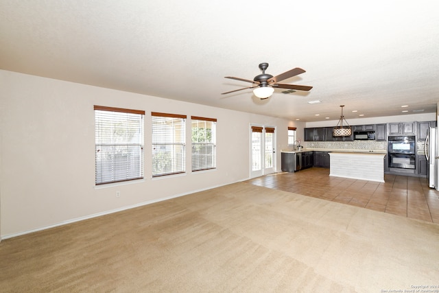 unfurnished living room featuring a textured ceiling, carpet, and ceiling fan