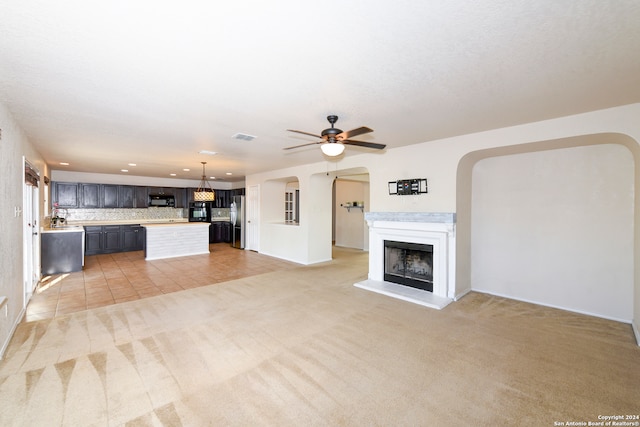 unfurnished living room with light carpet and ceiling fan