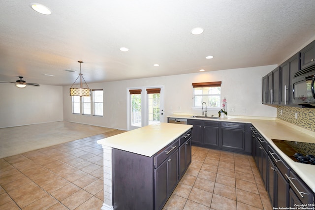 kitchen featuring black appliances, sink, a center island, pendant lighting, and light tile patterned floors