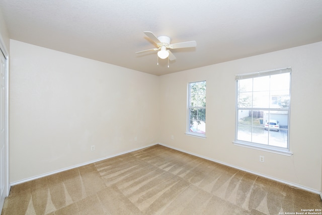 carpeted spare room featuring ceiling fan