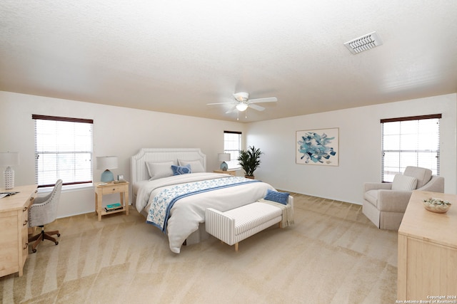 carpeted bedroom featuring multiple windows, a textured ceiling, and ceiling fan