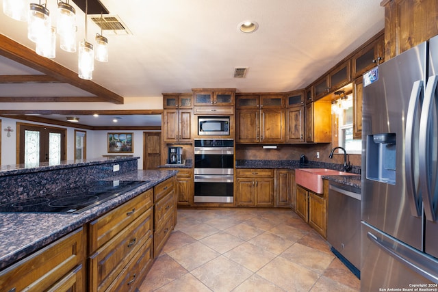 kitchen featuring appliances with stainless steel finishes, dark stone counters, sink, french doors, and decorative light fixtures