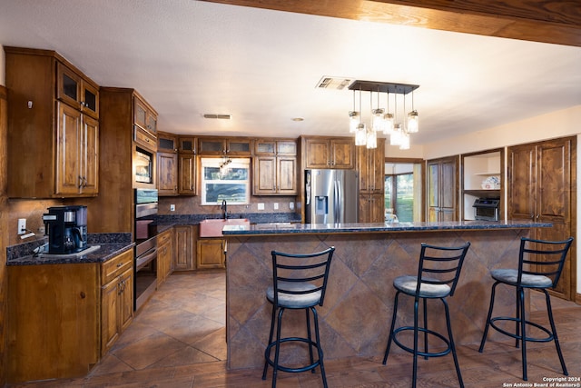 kitchen featuring a kitchen island, hanging light fixtures, stainless steel appliances, and dark stone countertops