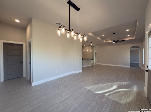 interior space with ceiling fan and a raised ceiling