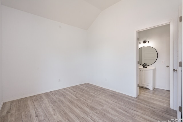 unfurnished room featuring sink, vaulted ceiling, and light hardwood / wood-style flooring