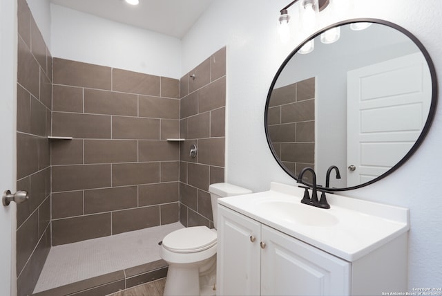 bathroom with vanity, toilet, and a tile shower