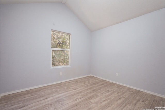 unfurnished room featuring light hardwood / wood-style floors and lofted ceiling