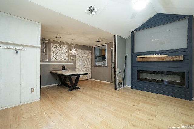 interior space with light hardwood / wood-style flooring, ceiling fan with notable chandelier, and vaulted ceiling