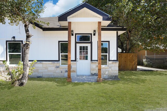 23238 Copper Canyon Dr, Elmendorf, TX 78112 - view of front facade featuring stone siding, a front lawn, fence, and a shingled roof