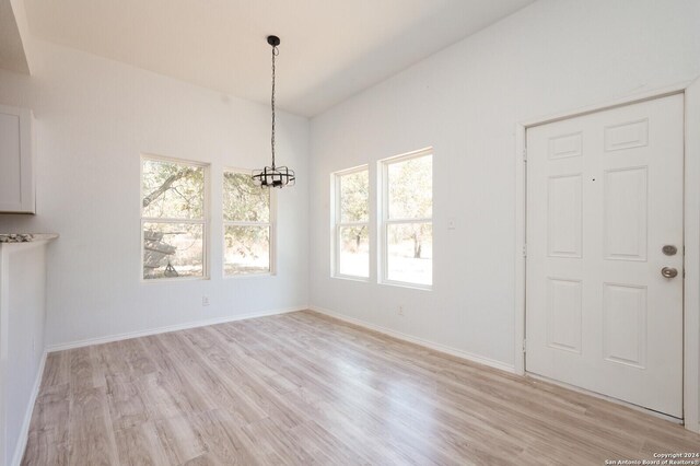 23238 Copper Canyon Dr, Elmendorf, TX 78112 - unfurnished dining area featuring light wood-type flooring, baseboards, a notable chandelier, and a healthy amount of sunlight