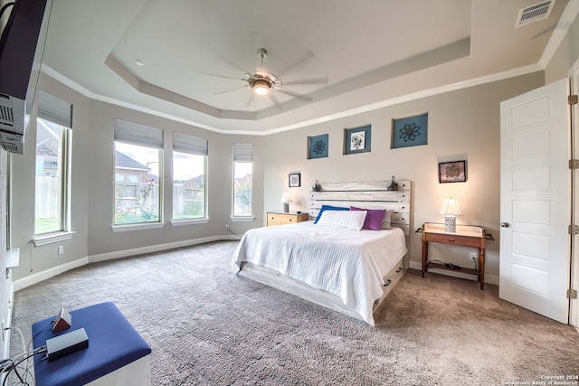 carpeted bedroom featuring ceiling fan, a raised ceiling, and ornamental molding