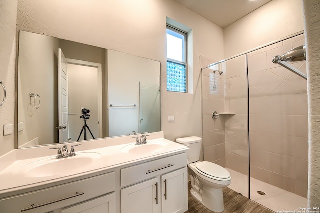 bathroom featuring toilet, hardwood / wood-style flooring, vanity, and a tile shower