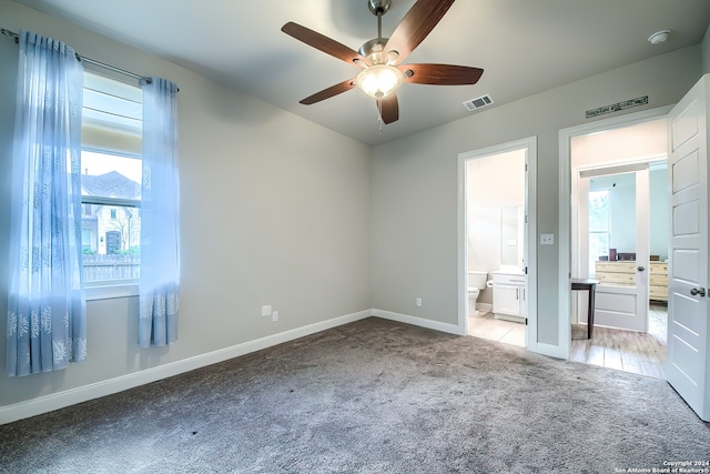 unfurnished bedroom with light colored carpet, connected bathroom, and ceiling fan