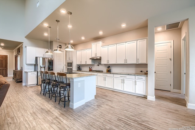 kitchen featuring appliances with stainless steel finishes, an island with sink, and white cabinetry