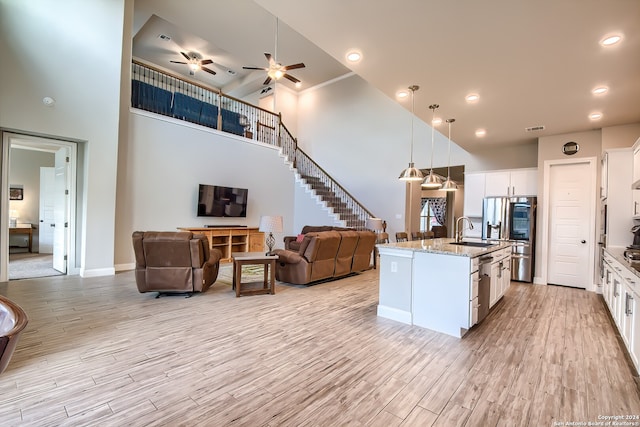 kitchen featuring white cabinetry, a towering ceiling, decorative light fixtures, and a kitchen island with sink