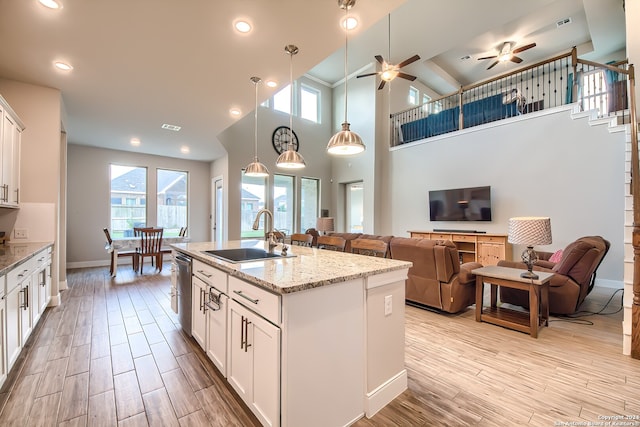 kitchen featuring white cabinetry, a healthy amount of sunlight, sink, and a kitchen island with sink