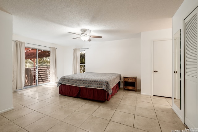 bedroom featuring ceiling fan, a textured ceiling, access to exterior, light tile patterned flooring, and a closet