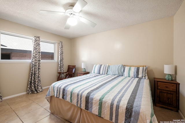 bedroom with a textured ceiling, light tile patterned floors, and ceiling fan