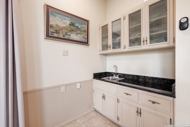 kitchen with white cabinetry, dark stone countertops, sink, and light tile patterned floors