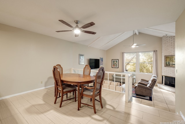 dining space with vaulted ceiling with beams, ceiling fan, and a brick fireplace