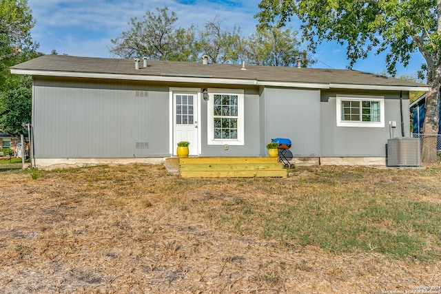 back of house with cooling unit and a lawn