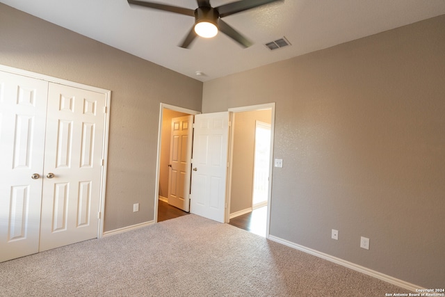 unfurnished bedroom with dark colored carpet, a closet, and ceiling fan