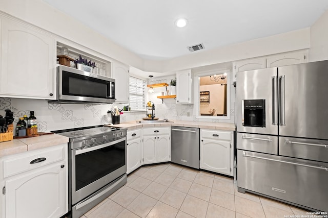 kitchen with stainless steel appliances, sink, tile counters, and white cabinets