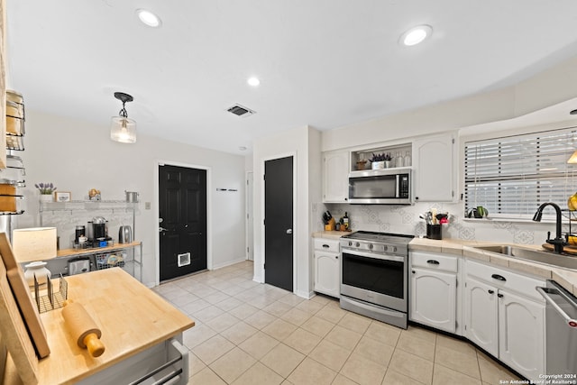 kitchen featuring sink, white cabinetry, decorative light fixtures, and stainless steel appliances