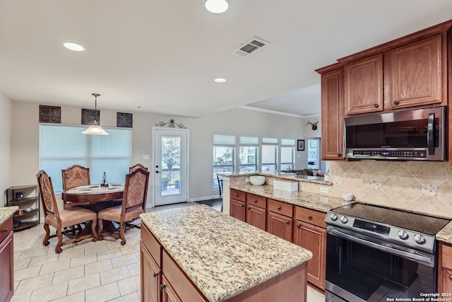 kitchen featuring decorative backsplash, hanging light fixtures, light stone counters, stainless steel appliances, and a center island