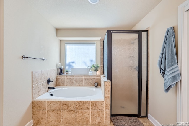 bathroom featuring separate shower and tub and a textured ceiling